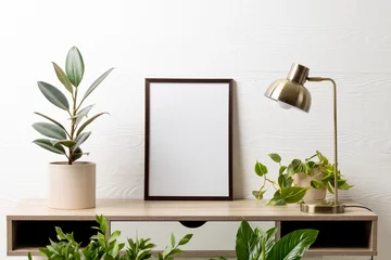 Fotobehang Historisch gebouw Black empty frame with copy space, lamp and plants in pots on table against white wall