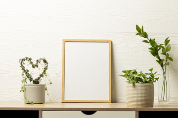 Wood empty frame with copy space and plants in pots on desk against white wall