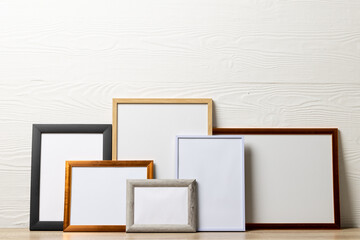 Colourful empty frames with copy space on table against white wall