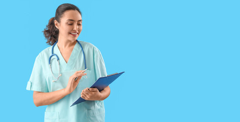 Fototapeta na wymiar Female medical assistant with clipboard on light blue background with space for text