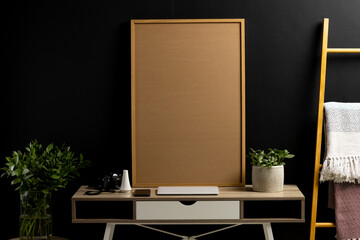 Wood empty frame with copy space, plants and technology devices on desk against black wall