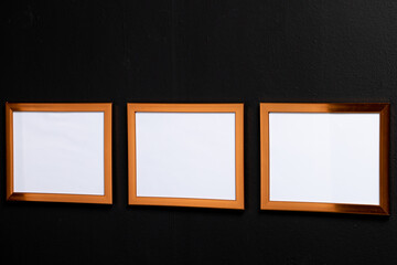 Brown empty frames with copy space on black wall