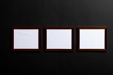 Brown empty frames with copy space on black wall