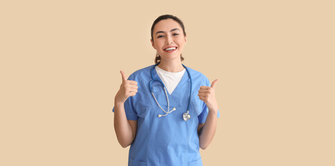 Female medical assistant showing thumb-up on beige background