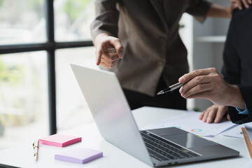 Team of business people pointing at laptop computer screen discussing financial management, income, taxes with data displayed on screen in preparation for meeting at office.