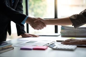 Two confident businessmen shaking hands during meeting in office and mutual investment in financial business that fits and succeeds in office.