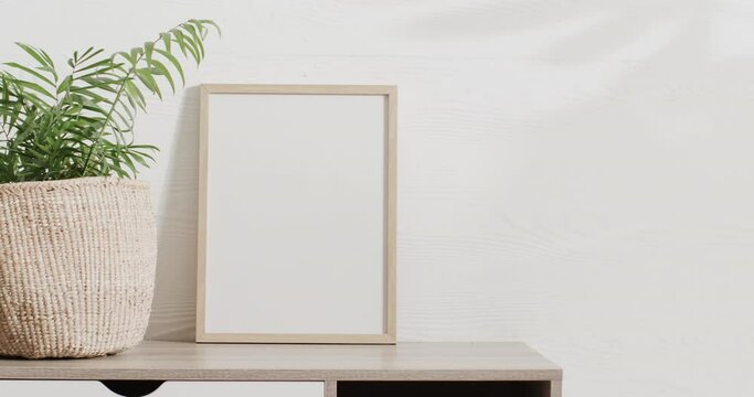 White frame and plant on desk with copy space against white wall