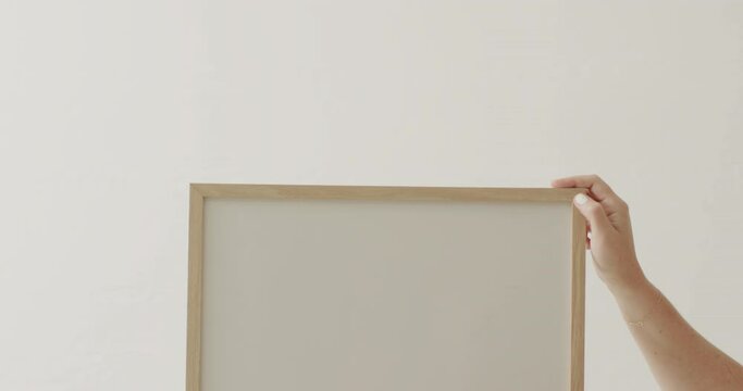 Hands of caucasian woman holding frame with copy space on white background against white wall