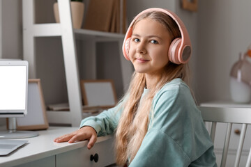 Little girl in headphones sitting at table