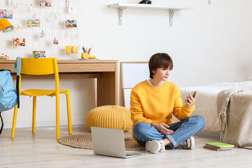 Teenage boy using mobile phone in bedroom