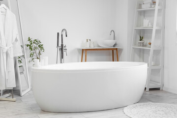 Interior of light bathroom with bathtub, sink and shelving unit