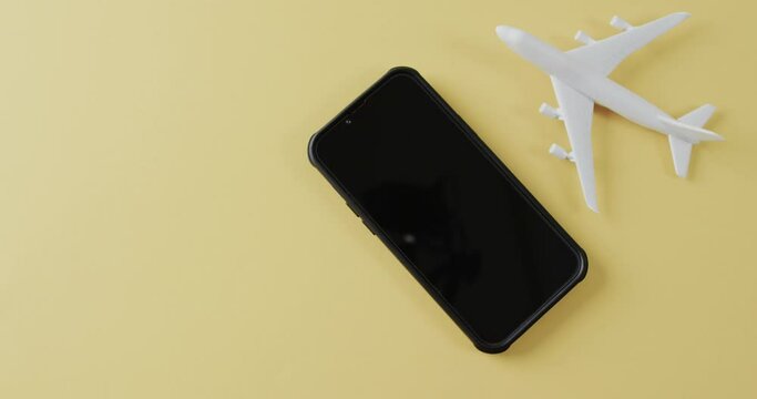 Close up of white plane model, smartphone and copy space on yellow background