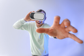 Young man using VR glasses on light background