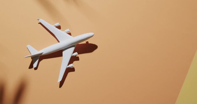 Close up of white airplane model with leaf shadow and copy space on yellow background