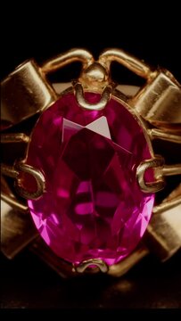 a ray of light falls on a golden ring with a red gem, creating glare on its faces, macro shot