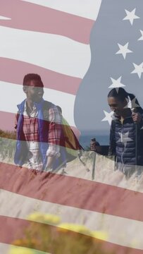 Animation of american flag over smiling diverse couple hiking in mountains