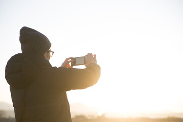 スマホで朝日を撮影する男性