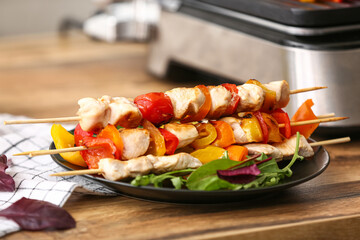 Plate with tasty chicken skewers and vegetables on table, closeup