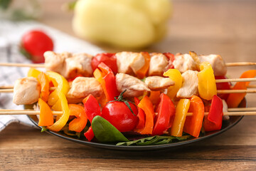 Plate with tasty chicken skewers and vegetables on table, closeup