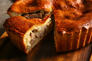 Board with delicious meat pie on grey grunge table