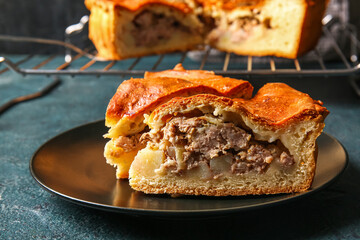 Plate with pieces of delicious meat pie on grey grunge table, closeup