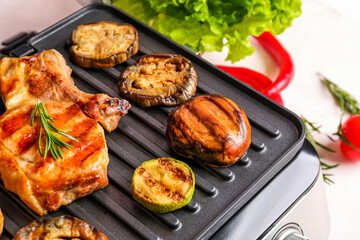 Modern electric grill with tasty steak and vegetables on light background, closeup