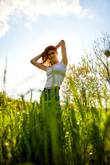 Naklejka na ściany i meble joyful woman posing in tall grass on a sunny day
