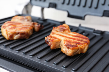 Delicious steaks on modern electric grill, closeup