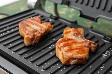 Delicious steaks on modern electric grill, closeup