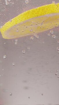 a slice of lemon falls into soda water on a white background