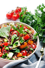 Quinoa tabbouleh salad with red cherry tomatoes, orange paprika, avocado, cucumbers and parsley. Traditional Middle Eastern and Arabic dish. White table background, top view