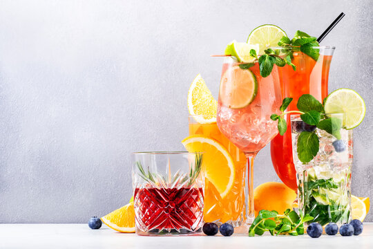 Trendy cocktails set: negroni, blueberry mojito, screwdriver, hurricane and french mule on gray background. Refreshing summer drinks
