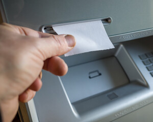 a man takes a check issued by an ATM, a check without inscriptions, a place for the text on the...