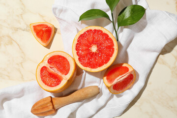 Composition with cut ripe grapefruits, juicer and plant branch on light background