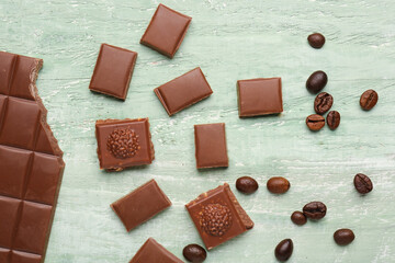 Composition with pieces of tasty chocolate and coffee beans on color wooden background