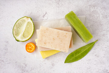 Stack of natural soap bars and citrus fruits on light background