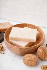 Bowl with natural soap bars and walnuts on light background, closeup