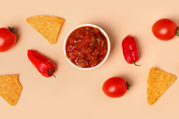 Composition with bowl of salsa sauce, vegetables and nachos on color background
