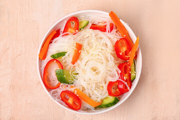 Bowl with tasty rice noodles and vegetables on light wooden table