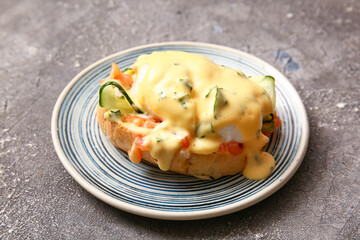 Plates with delicious egg Benedict on grey grunge table, closeup