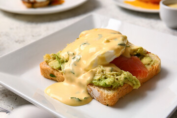 Plate with delicious egg Benedict on white table, closeup
