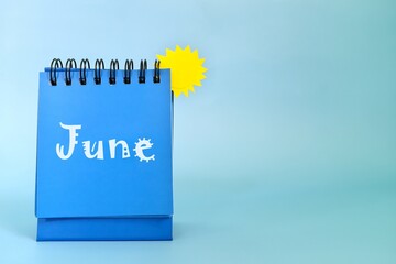 Selective focus of June month desk calendar on blue background with yellow sun and copy space. - obrazy, fototapety, plakaty