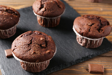 Board with tasty chocolate cupcakes on wooden background