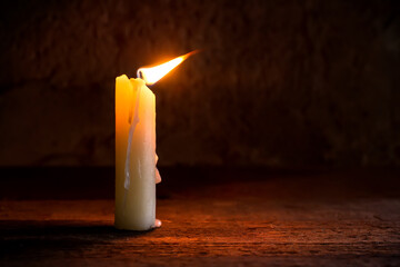 A lit candle in the breeze. A candle in the twilight. The flame of the candle fluctuates under the...