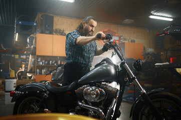 Fototapeta na wymiar Mature male biker on his new motorbike in garage