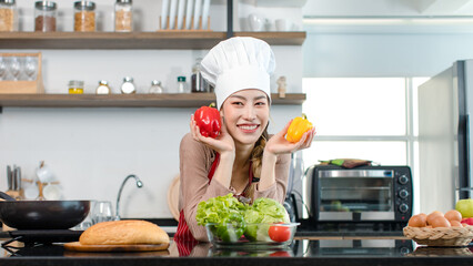 Asian young female chef wears white tall cook hat and apron smiling posing holding green apple...