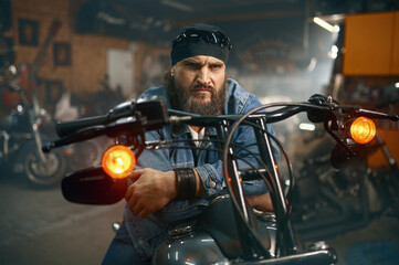 Handsome bearded man testing new motorbike in garage store