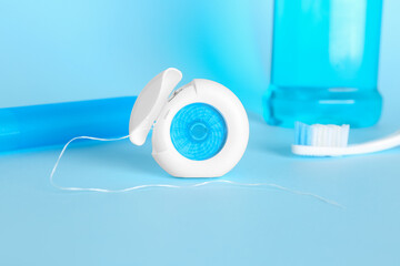 Dental floss and toothbrush on blue background