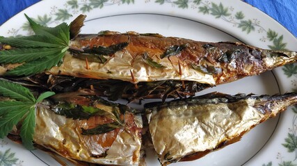 cannabis (hemp) food. classic cannabis leaf lies on a baked fish stuffed with young leaves of marijuana. homemade fish food