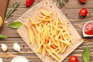 Composition with tasty french fries, pepper and sauces on wooden background